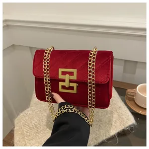 Detail of red velvet handbag with quilted stitching and gold rectangular swivel lock