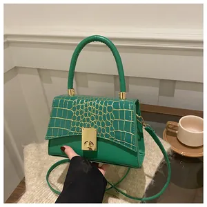 Detail der grünen Handtasche mit goldener Krokoprägung und metallischem Drehverschluss