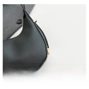 Detail showing Saffiano leather texture and gold hardware on black crescent bag