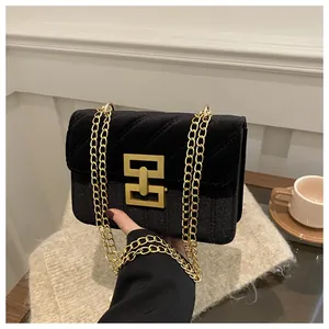 Detail of black velvet crossbody bag with V-quilted texture and gold chain strap