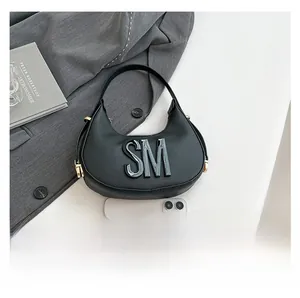 Close-up of black crossbody bag with SM logo and size comparison with a smartphone