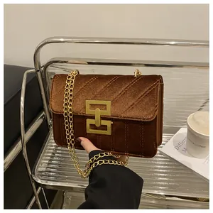 Detail of dark brown velvet crossbody bag with gold chain and quilted texture