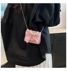 Pink mini crossbody bag featuring a large organza bow and elegant pearl carry handle