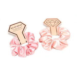 Due elastici in raso rosa su un cartoncino a forma di diamante per regali da damigella
