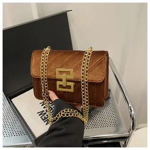 Detail of brown velvet crossbody bag with quilted patterns and gold metal chain strap