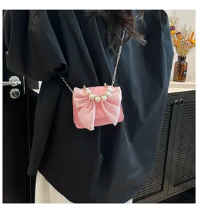 Close-up of pink mini crossbody bag featuring large bow, white pearls and gold chain strap