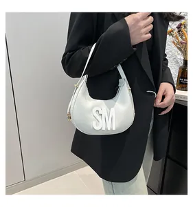 Close-up of white hobo bag with 3D SM letter logo and elegant gold metal zipper detail