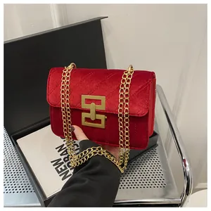 Close-up of red velvet shoulder bag with gold H-buckle and diagonal quilting