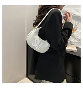 White leather dumpling bag with SM embossed letters worn with a black blazer