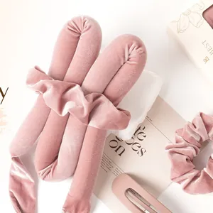 Bovenaanzicht van de roze fluwelen heatless haarkrulset met scrunchies en clip