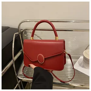 Details einer roten matten Lederhandtasche mit goldener Schnalle und Rundgriff