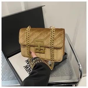 Close-up of golden velvet crossbody bag with diagonal quilting and metal chain strap
