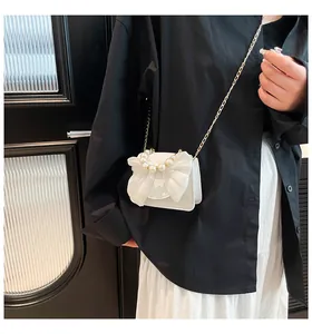 Detail of white mini crossbody bag with organza bow and pearl handle on model