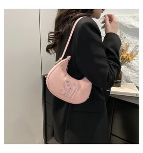 Detailed view of pink dumpling crescent bag with embossed SM logo on lychee leather
