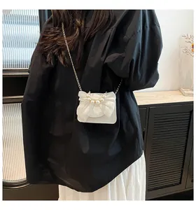 Close-up of white crossbody bag featuring organza bow and pearl details on leather