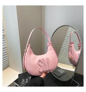 Detail of pink crescent bag with SM lettering and textured faux leather finish