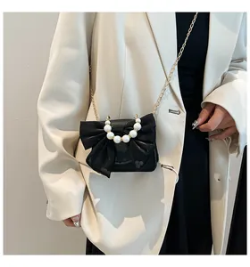 Detail of elegant black crossbody bag with mesh bow and decorative pearl handle