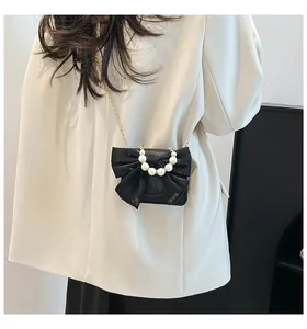Detail of black mini crossbody bag with oversized mesh bow and white pearl handle