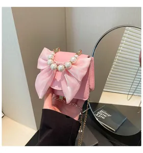 Close-up of pink crossbody bag featuring a satin bow and large pearl handle detail