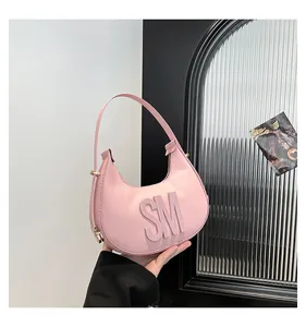 Detailed view of pink pebble leather hobo bag with embossed letters and gold buckle