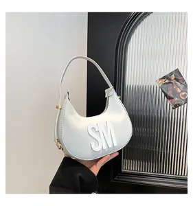 Detailed close-up of white leather crescent bag with 3D SM letter logo and gold hardware