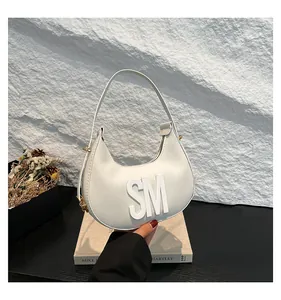 Detail view of white textured leather crescent bag with 3D SM letter branding