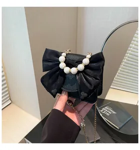 Close-up of black leather bag with large mesh bow and elegant pearl carry handle