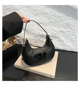 Detail of black leather dumpling bag with 3D SM letters and gold metal hardware