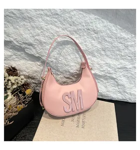 Detail of pink half-moon bag featuring 3D embossed SM letters and pebbled leather texture