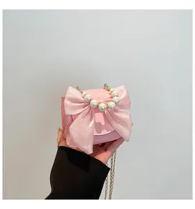 Detailed shot of pink mini handbag with satin bow and decorative pearl handle