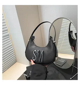 Detail of black leather dumpling bag with 3D SM metal logo and gold zipper hardware