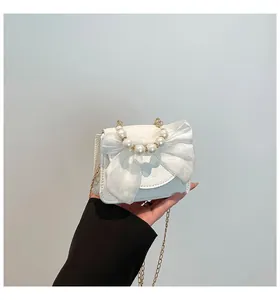 Detail of white lychee leather mini bag with organza bow and pearl handle grip