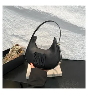 Detail of black leather dumpling bag with metal zipper and SM letter ornament