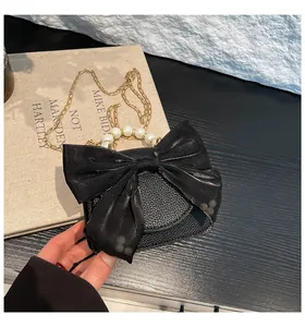 Close-up of mini black leather bag with large silk bow and pearl handle details