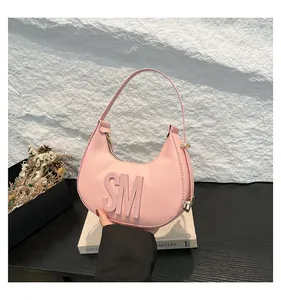 Close-up of pink crescent dumpling bag with 3D SM logo and lychee grain leather texture