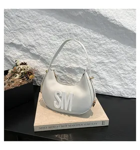 Detail of ivory hobo bag featuring 3D letters on cross-grain leather and metal zipper