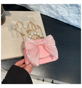 Close-up of pink mini bag with organza bow, pearl handle, and litchi grain texture