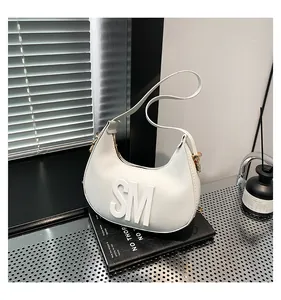 Detail of white leather crescent hobo bag with embossed SM letters and gold hardware