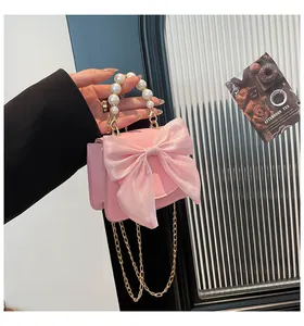 Detailed shot of pink textured mini bag with oversized bow and elegant pearl handle