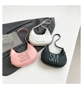 Detailed view of three hobo shoulder bags in pink, white, and black with SM letter detail
