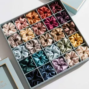 Vue détaillée de 25 chouchous en satin de soie organisés dans une boîte cadeau bleue