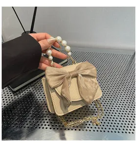 Detail of beige faux leather bag featuring a large silk bow and pearl-embellished handle