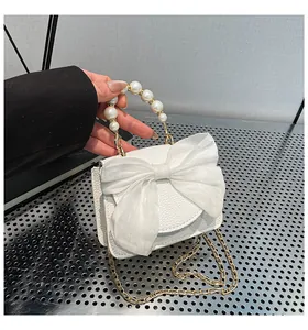 Detailed view of mini white litchi grain bag with organza bow and pearl handle