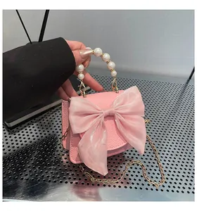 Close-up of pink mini handbag with large fabric bow and white pearl handle detail