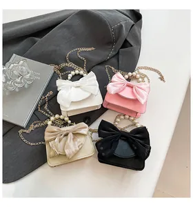 Detail of four colorful mini crossbody bags with chic silk bows and pearl handles