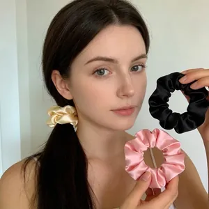 Vue détaillée des chouchous en satin lisse noir et rose avec un design élastique ondulé