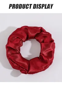 Détail du chouchou en satin rouge foncé avec texture soyeuse et surface en tissu brillant
