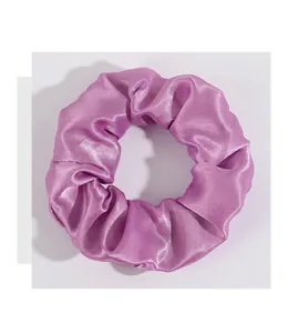 Gros plan du chouchou en satin violet montrant la texture brillante et le tissu plissé