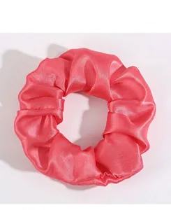 Gros plan sur un chouchou en satin rose vif avec une texture soyeuse et des plis délicats