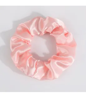 Detailansicht eines rosa Satin-Haargummis mit seidiger Textur und elastischem Innenband